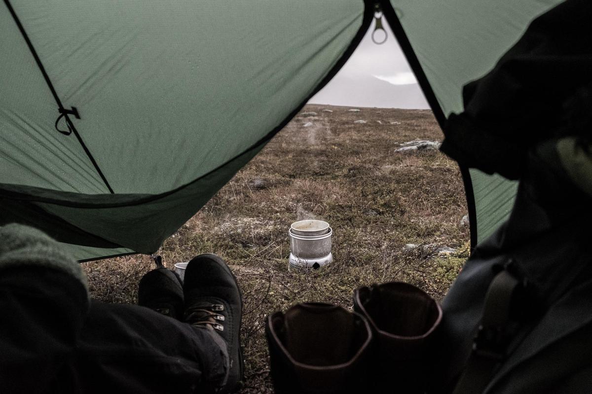 Sitting inside of a tent looking out the opening at a campsite